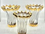 trois vases en verre doré posés sur une table blanche