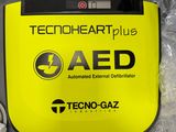 a yellow aed box with a charger on top of it