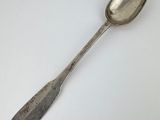 une cuillère en argent posée sur une surface blanche, avec une petite cuillère au milieu
