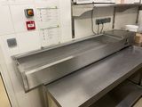 plan de travail en acier inoxydable dans une cuisine professionnelle, avec un micro-ondes fixé au mur