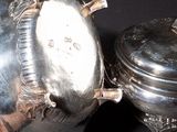 someone is holding a silver tea pot and a silver tea pot