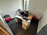 a desk with two computers and a chair in the corner