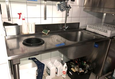un évier en inox dans une cuisine où le plan de travail est encombré