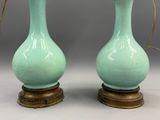 pair of green vases sitting on top of a wooden table