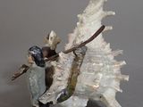 a figurine of a man riding a horse next to a sea shell