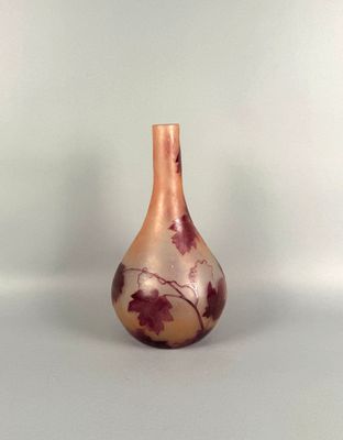 a small glass vase with leaves painted on it sitting on a table