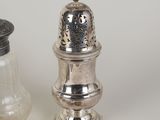 a salt and pepper shaker next to some coins
