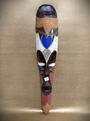 a close up of a wooden mask hanging on a wall