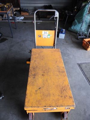a yellow bench sitting in a garage next to a hand truck