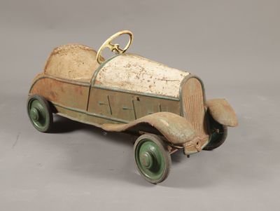 Une petite voiture ancienne est posée sur une surface grise
