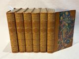 six antique books lined up in a row on a white surface