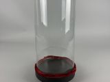 clear glass bell jar with red base on a white background