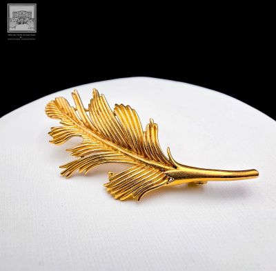a picture of a gold leaf brooch on a white plate