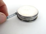 a person measuring the size of a coin with a tape
