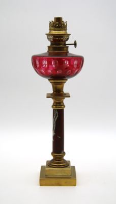 une lampe en verre rouge posée sur un pied doré