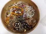 a wooden bowl filled with lots of jewelry on a table