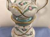 a tea pot sitting on top of a stack of tea cups