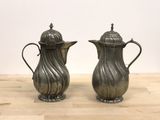 pair of antique silverplated coffee pots on a wooden table