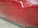 a close up of a red car ' s paint on the side of the road