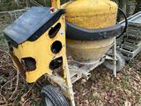 a yellow cement mixer sitting on a cart in the woods