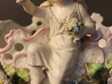 a figurine of a girl sitting on a clam shell