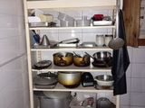 many pots and pans on a shelf in the kitchen