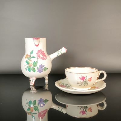 a tea pot and cup sitting on a table next to each other