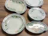 several plates with floral designs are arranged on a wooden table