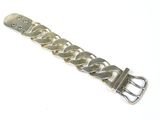 une image montrant un gros plan d'un bracelet en métal posé sur une surface blanche