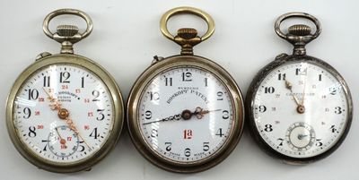 trois types différents de montres de poche posées sur une surface blanche