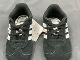 a pair of black and white baby shoes with a tag on them