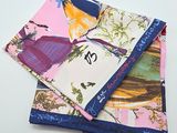 three different colored handkerchiefs on a white surface with a black tag