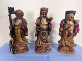 trois figurines représentant trois hommes portant un chapeau et une barbe, sur un fond bleu
