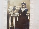 an old photo of a woman sitting at a table with a vase of flowers