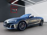 a grey audi convertible parked in front of a black wall