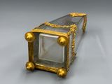 une boîte ancienne en or et en verre, entourée d'une chaîne