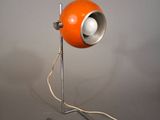 une lampe orange posée sur un pied en métal