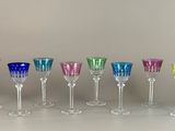 Plusieurs verres à vin de différentes couleurs sont alignés sur une table.