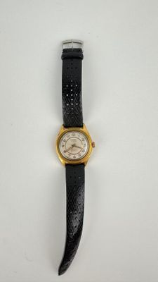 gros plan d'une montre sur une surface blanche avec un bracelet noir