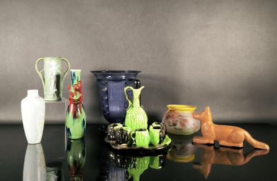 many different vases on a black table with a gray background
