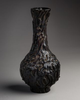 a black vase sitting on a table with a gray background