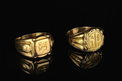 two gold rings with initials on them on a black surface