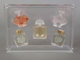 three bottles of perfume in a clear display case