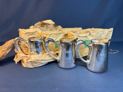 three silver coffee mugs sitting next to each other on a blue surface