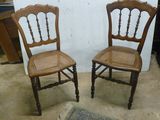 une paire de chaises anciennes en bois avec des dossiers en rotin dans un salon