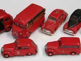 cinq petites voitures rouges et un bus posés sur une surface blanche