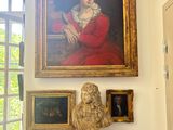 a statue of a woman in a red dress in front of a painting
