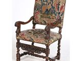 une vieille chaise dont le dossier est recouvert d'une tapisserie
