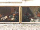 two paintings on the wall of a building with a cat sitting on a table in front of them