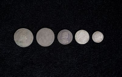 five silver coins in a row on a black surface